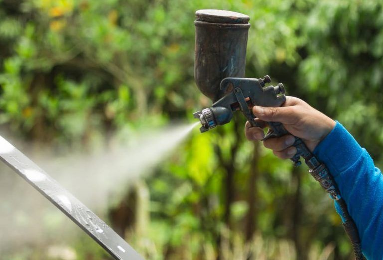 A person is spraying paint on a piece of metal.