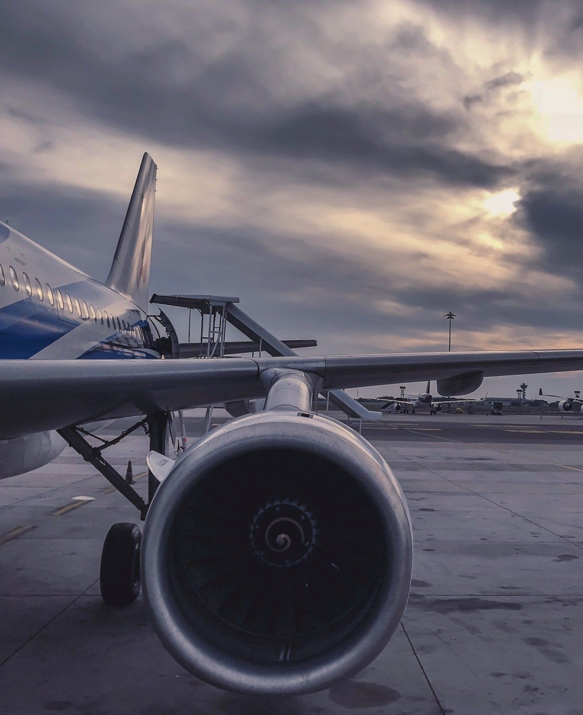 A plane is parked on a runway with a cloudy sky in the background