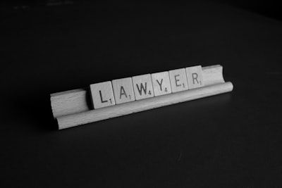 A black and white photo of scrabble tiles that spell out the word lawyer.