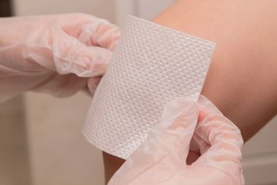A person is putting a bandage on another person 's arm.