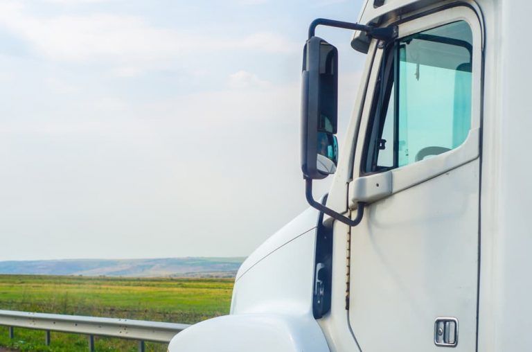 A white semi truck is parked on the side of the road.