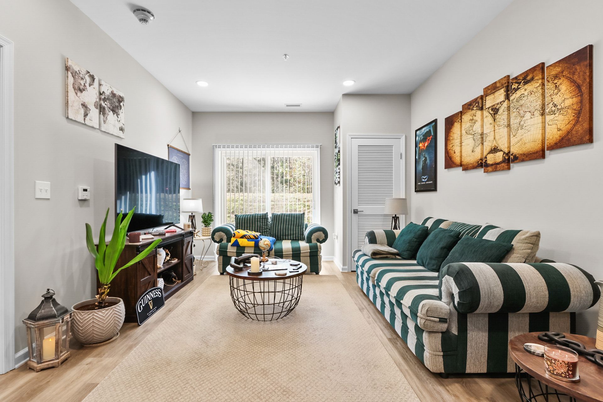 Living room with striped sofas, coffee table, TV, and decorative artwork.