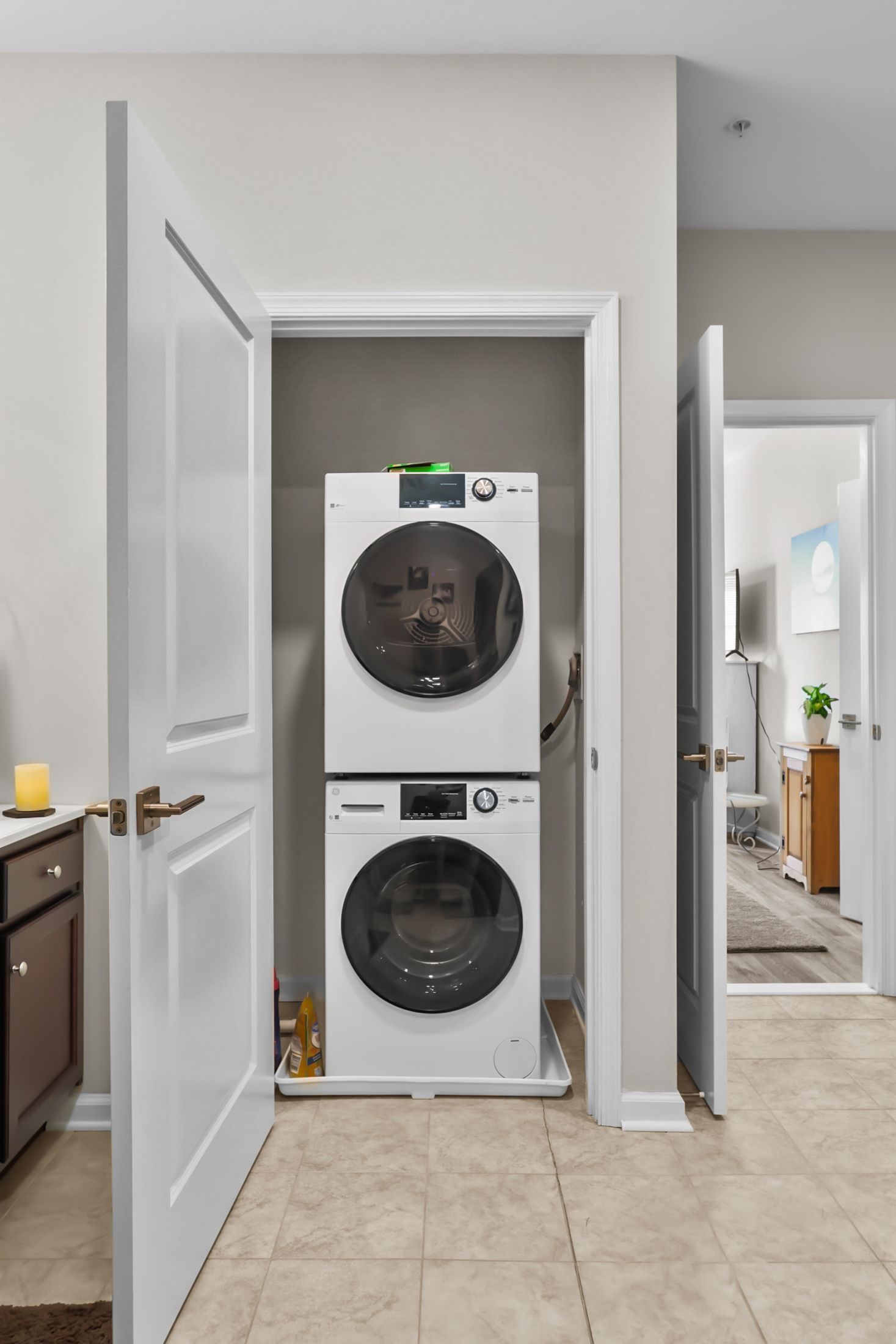 Stacked white washer and dryer in a small laundry closet, with open doors.