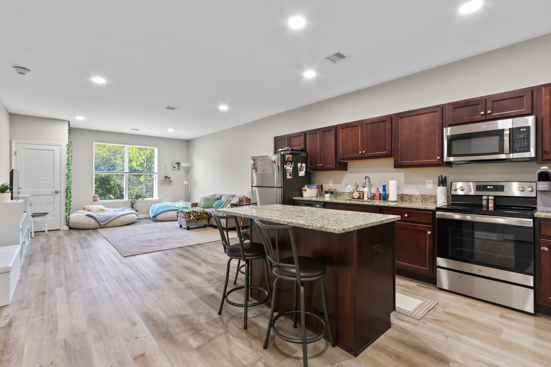 Open-plan living space with kitchen, island with stools, and living room with large windows.