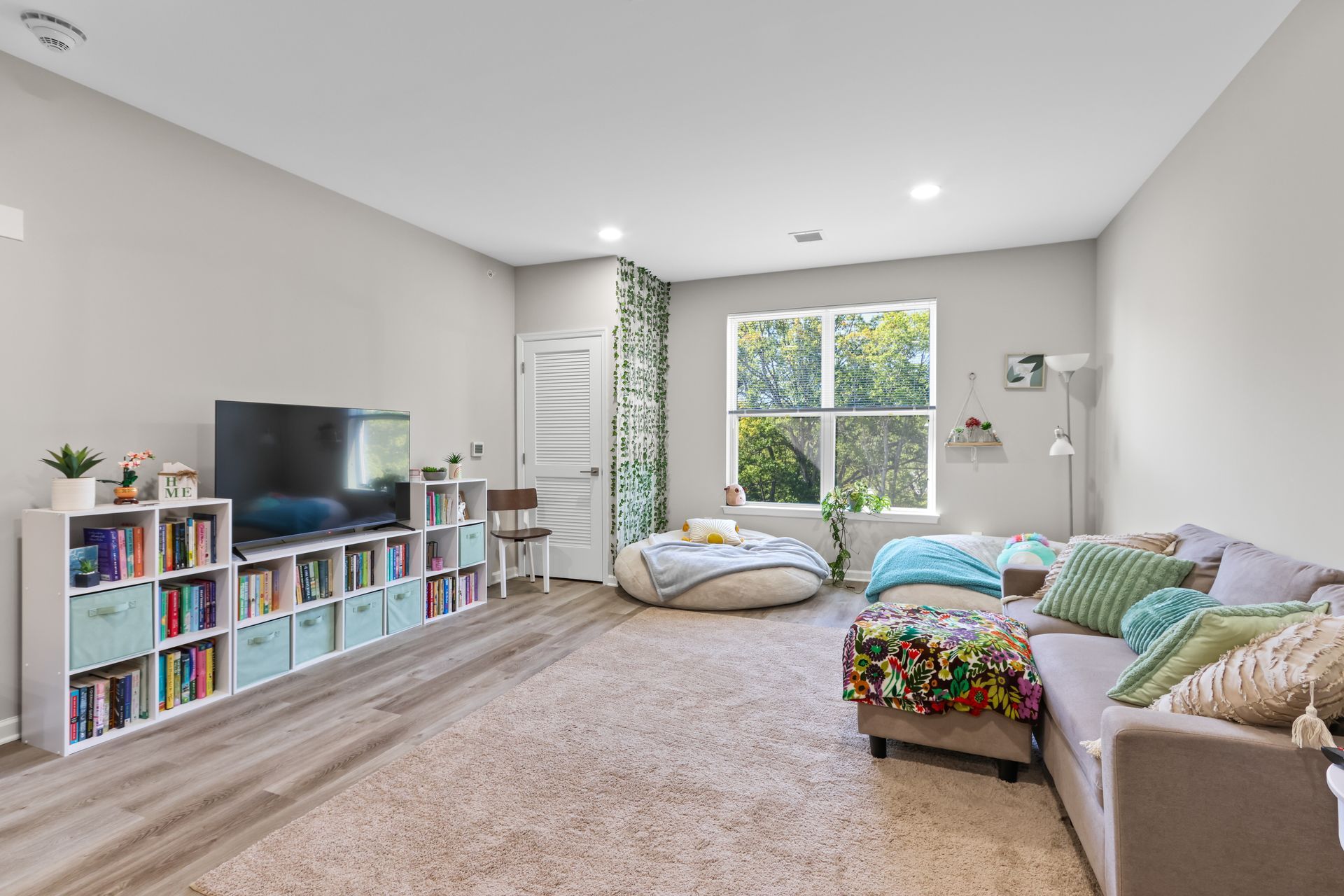 Living room with bookshelf, TV, sectional sofa, and a large window.