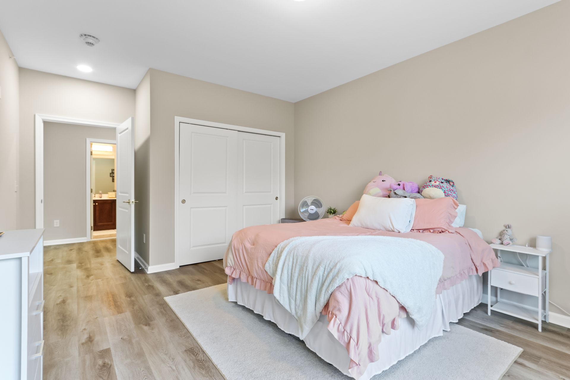 Bedroom with bed, closet, dresser, rug, and open door to a bathroom.