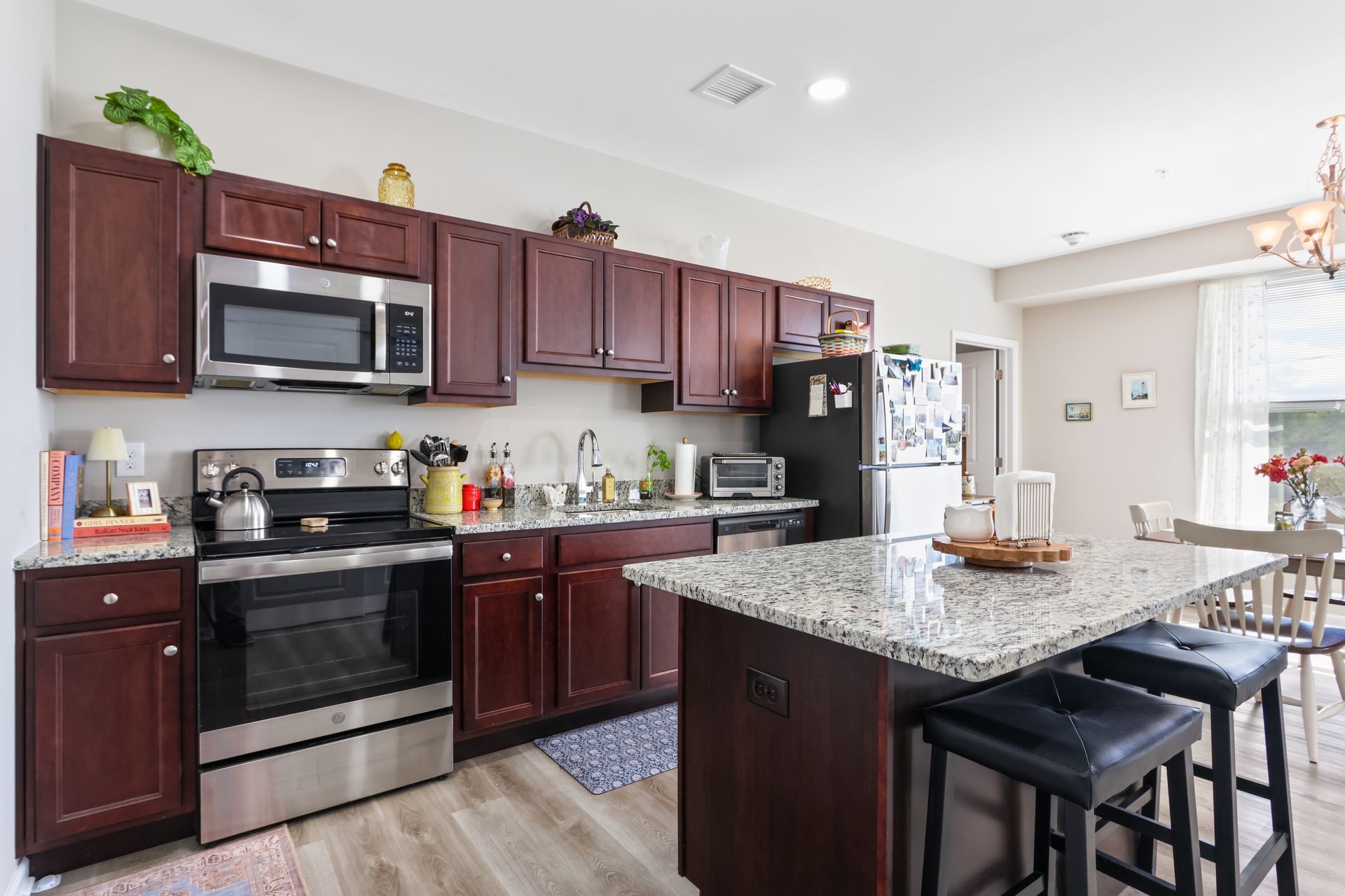Kitchen with dark cabinets, stainless steel appliances, and a granite island with stools.