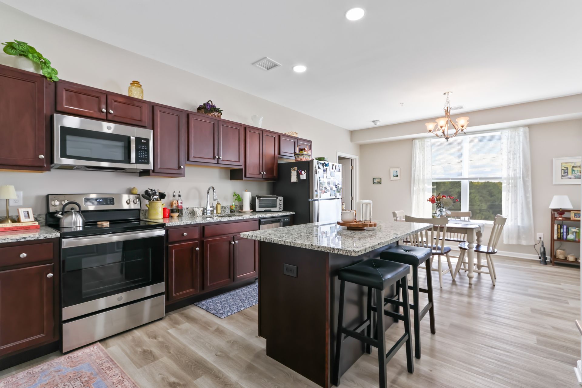 Kitchen with dark cabinets, stainless steel appliances, granite island, and dining area.