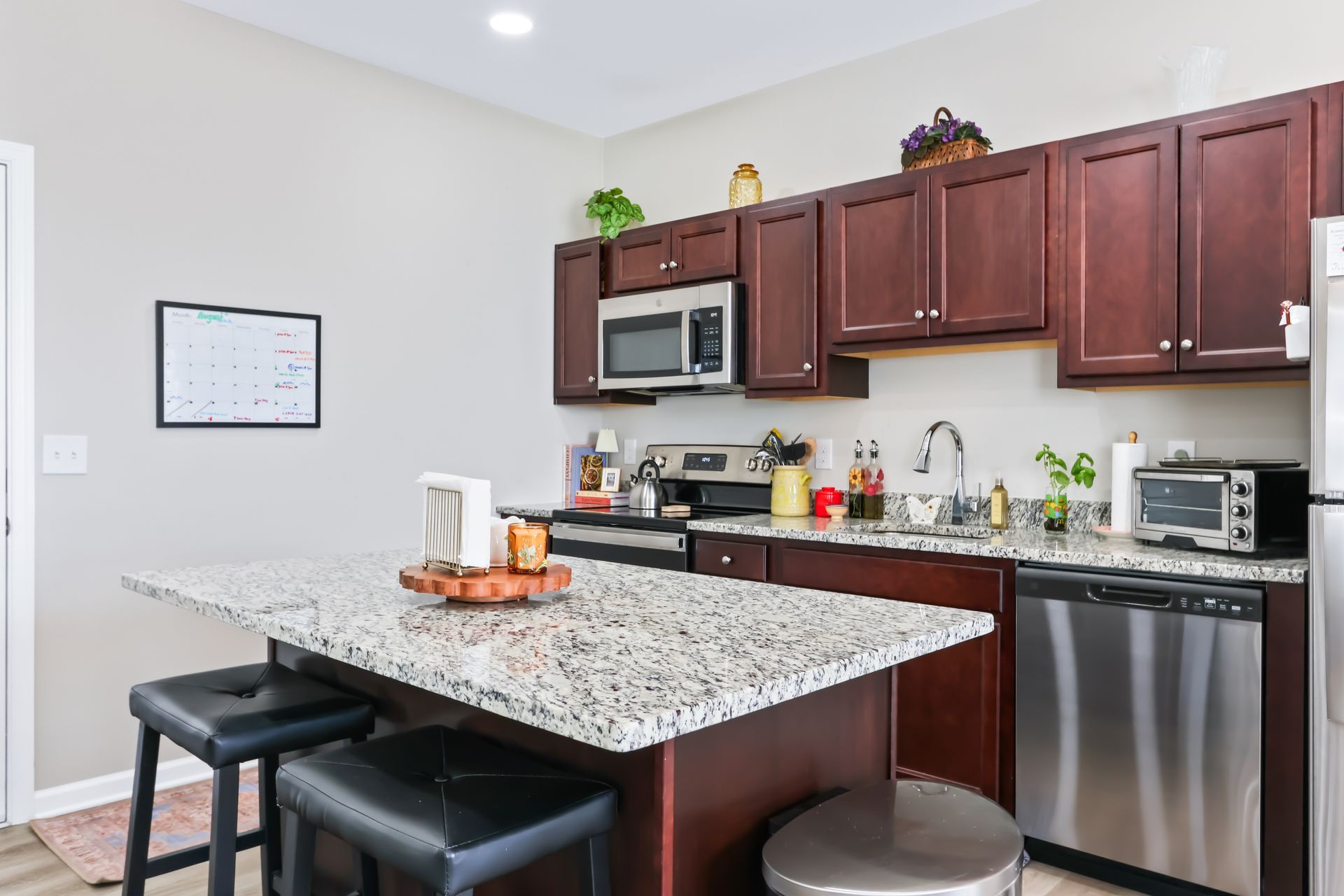 Modern kitchen with granite island, dark wood cabinets, and stainless steel appliances.
