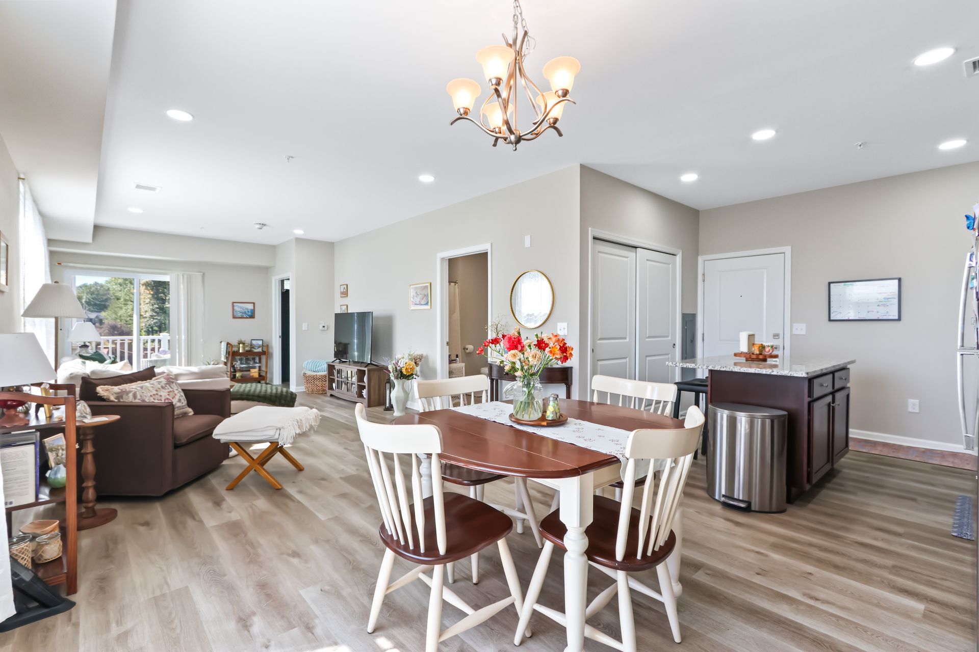 Open-concept living space with dining area, kitchen island, and a living room with a brown sofa and natural light.