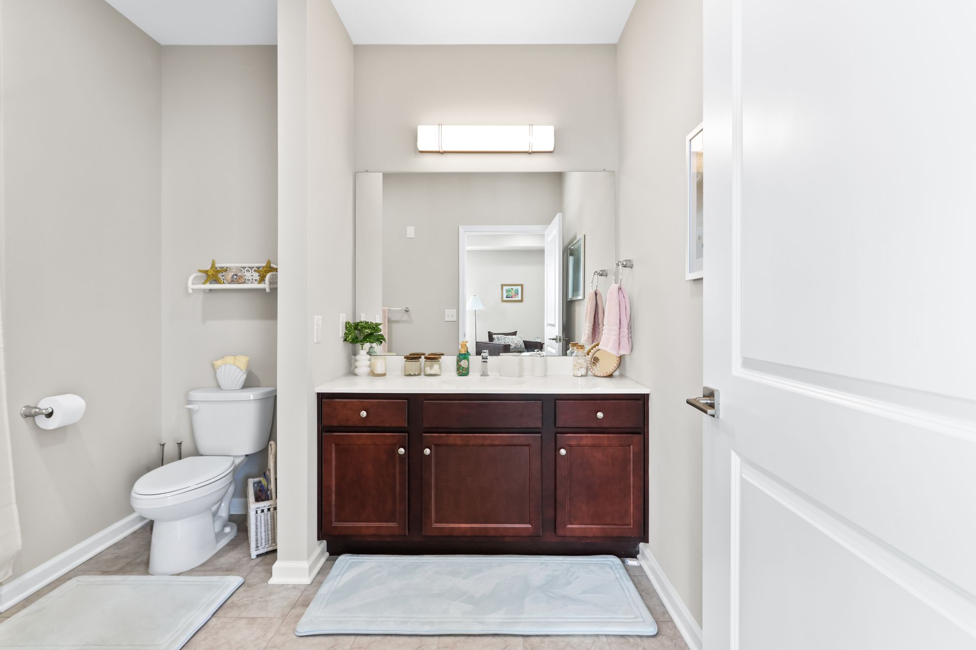 Bathroom with a vanity, toilet, and light-colored walls. A door is open to the right.