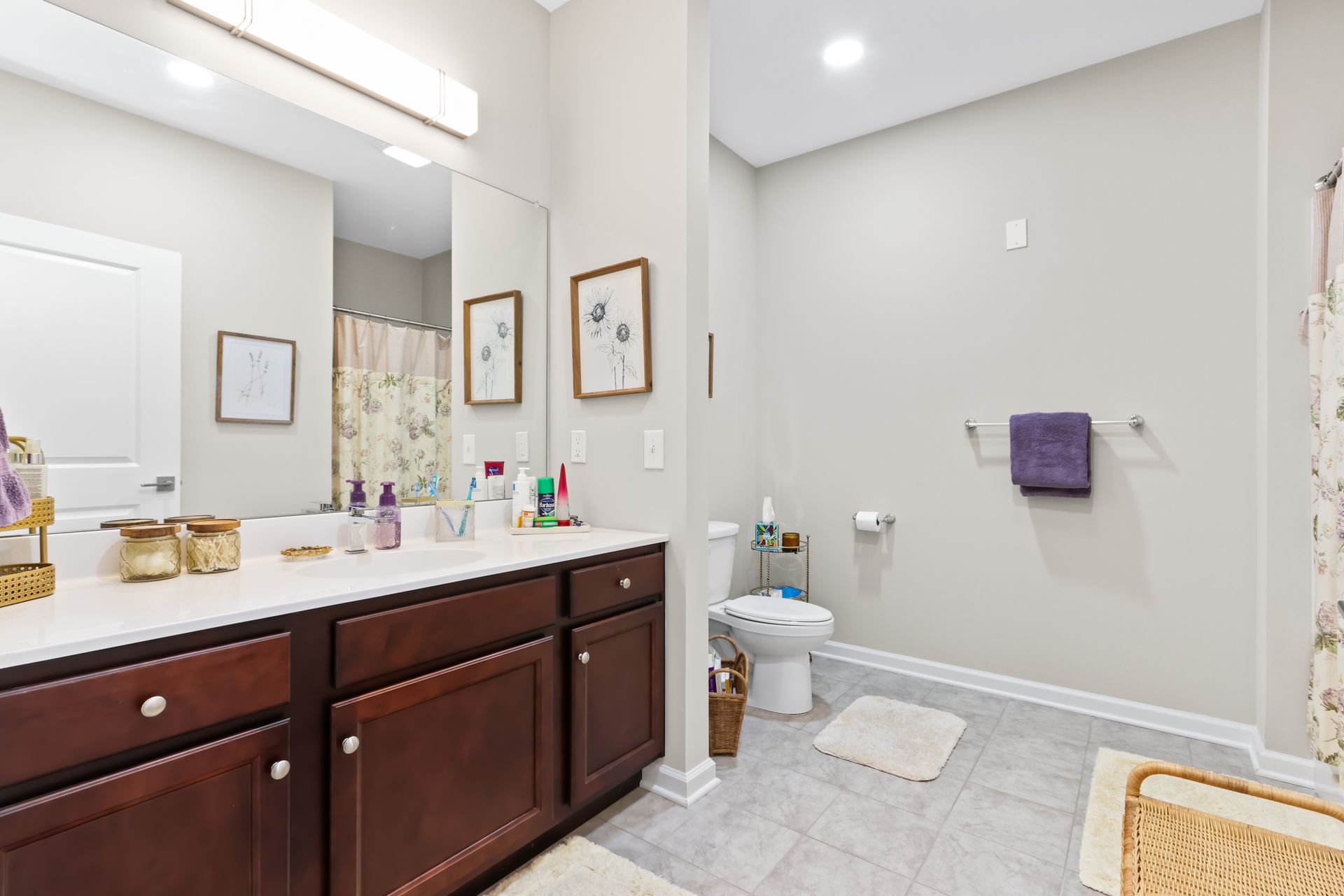 Bathroom with white countertop, dark cabinets, a toilet, and light gray walls.