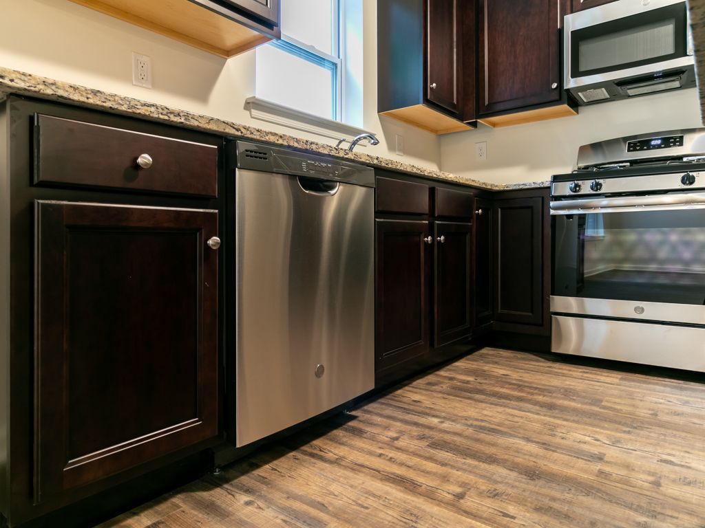 Dark wood kitchen cabinets with stainless steel appliances and wood-look flooring.