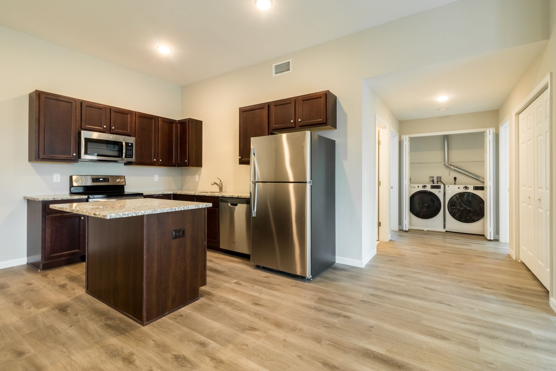 Kitchen with dark cabinets, stainless steel appliances, and laundry area visible.