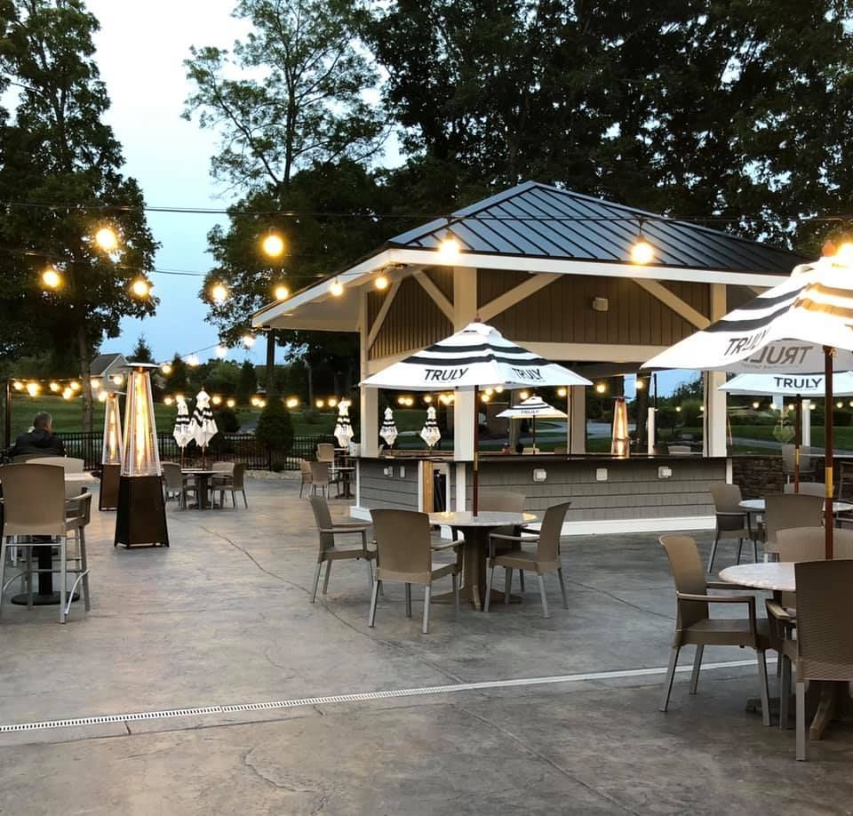 Outdoor bar area with tables, umbrellas, and a pavilion under string lights.