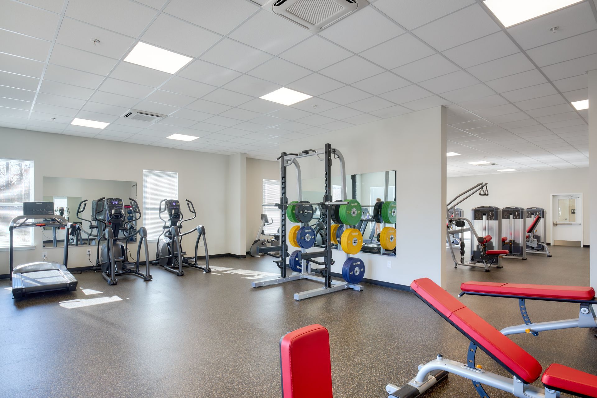 Gym with exercise equipment like treadmills, weights, and weight benches.