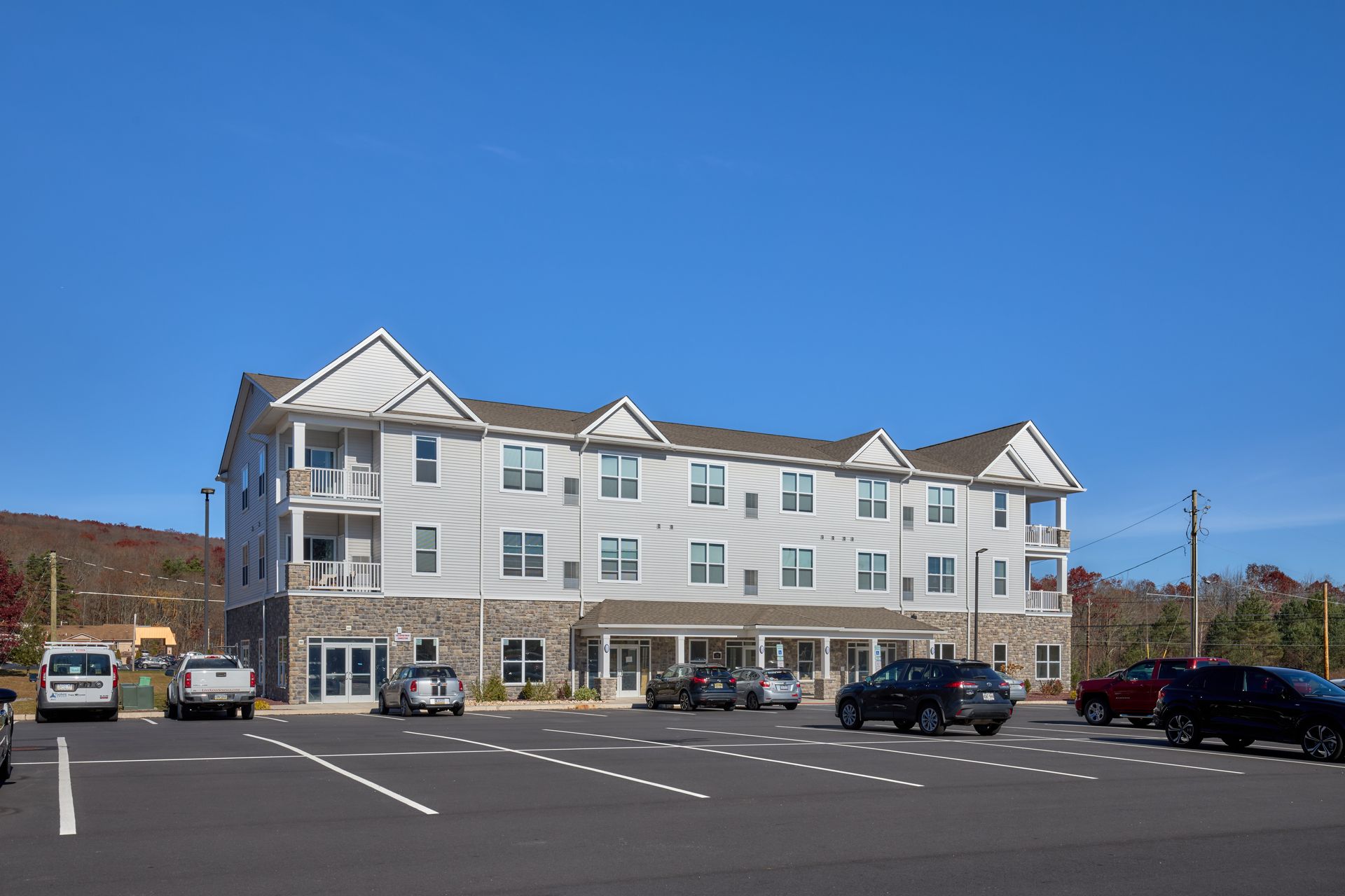 Multi-story apartment building with a large parking lot on a sunny day.