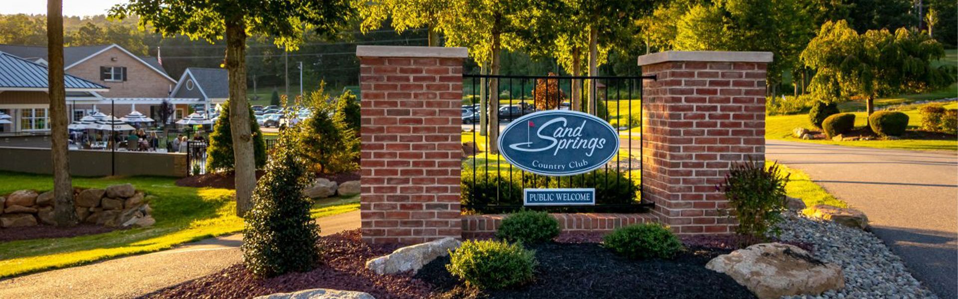 Entrance to The Springs with brick pillars, sign, and landscaping.