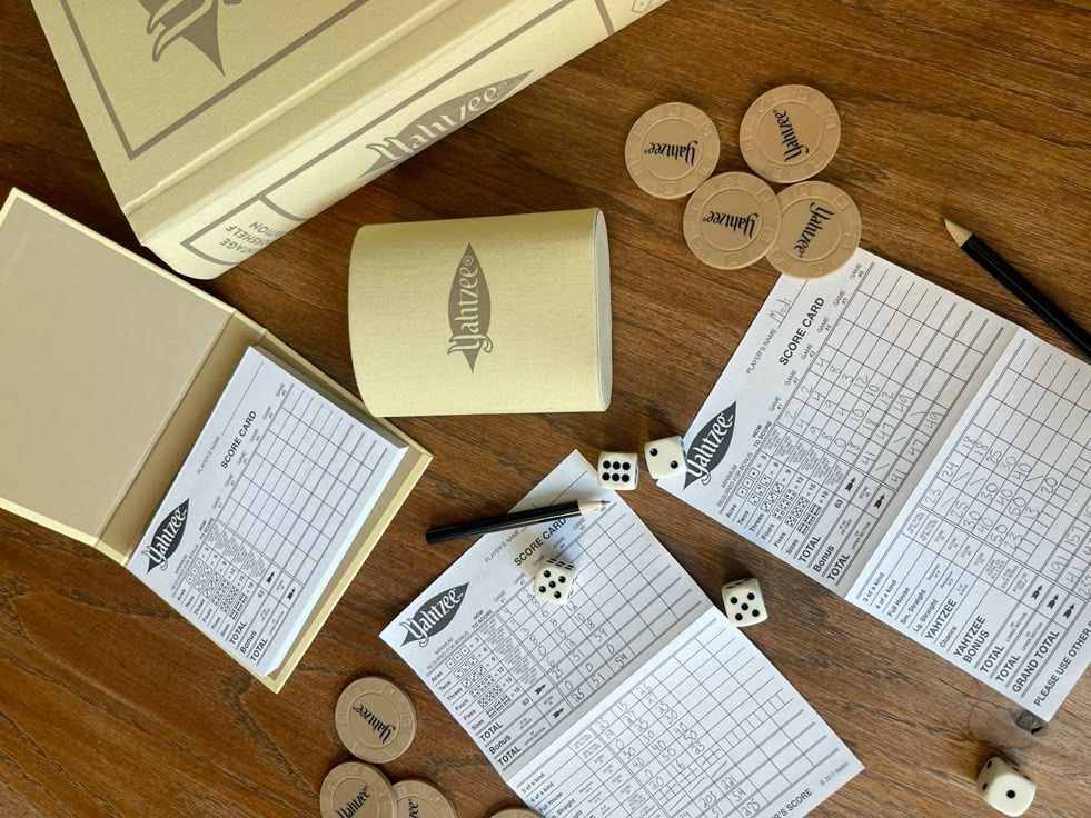 Yahtzee game night setup Yahtzee board game setup on a wooden table with scorecards, dice, pencils, and chips for a cozy game night