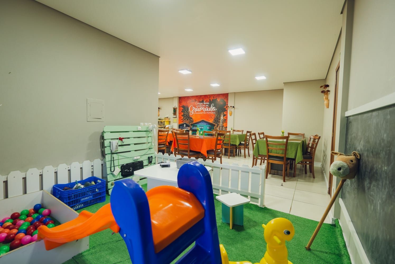 Área de lazer com escorregador, piscina de bolinhas e mesas.