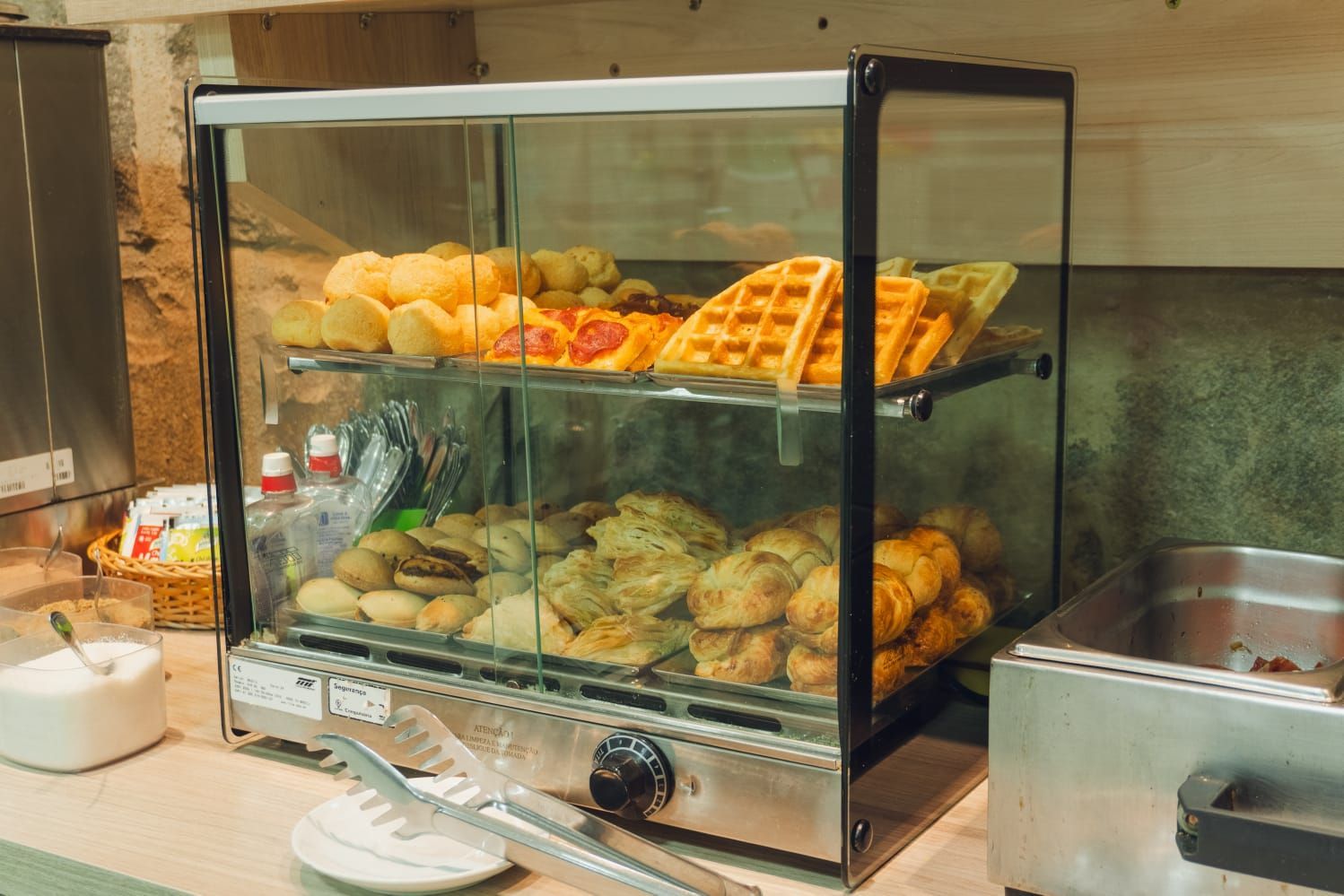Vitrine com doces: waffles, croissants e outros produtos assados em um bufê.