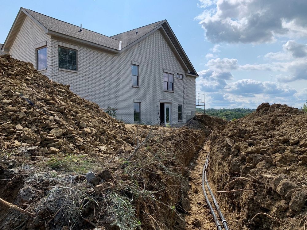 A house is being built on a hill with a large pile of dirt in front of it.