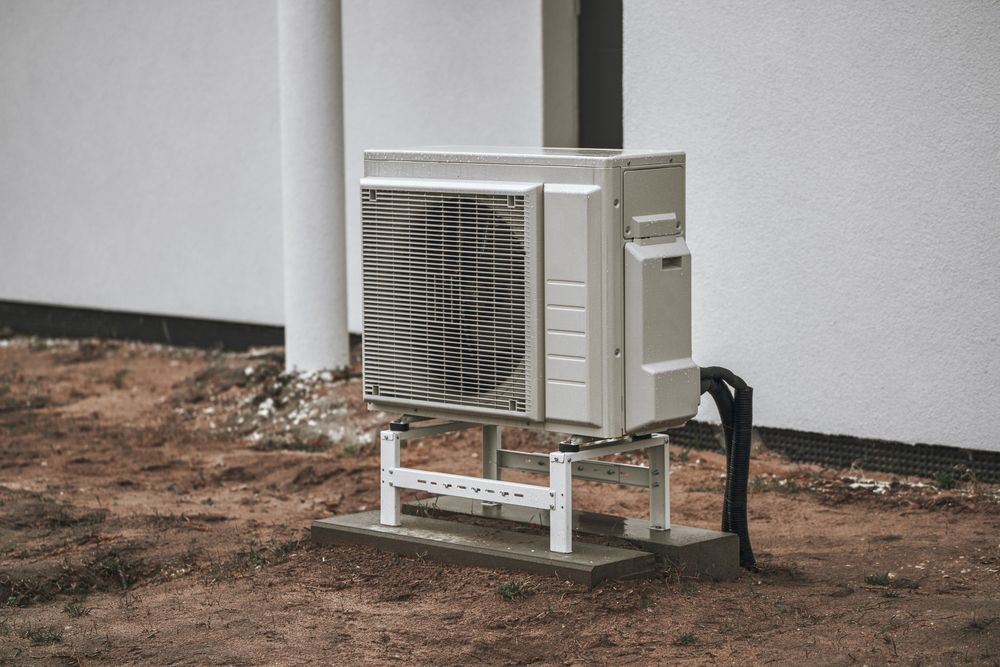 A large air conditioner is sitting outside of a building.