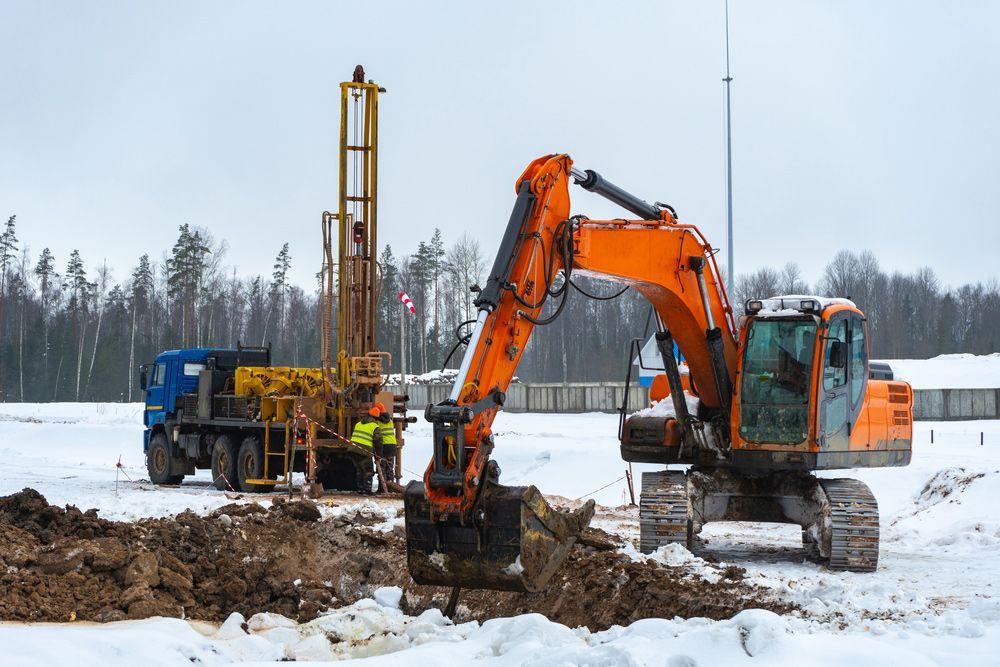 An excavator is digging a hole in the snow.