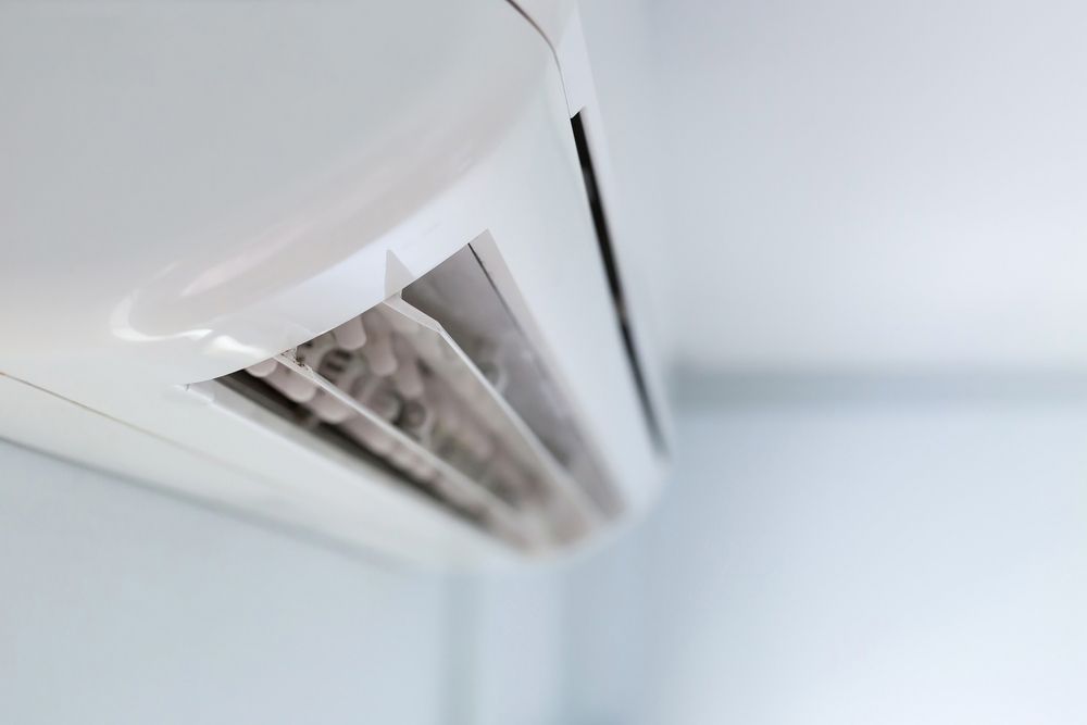 A close up of a white air conditioner hanging on a wall.