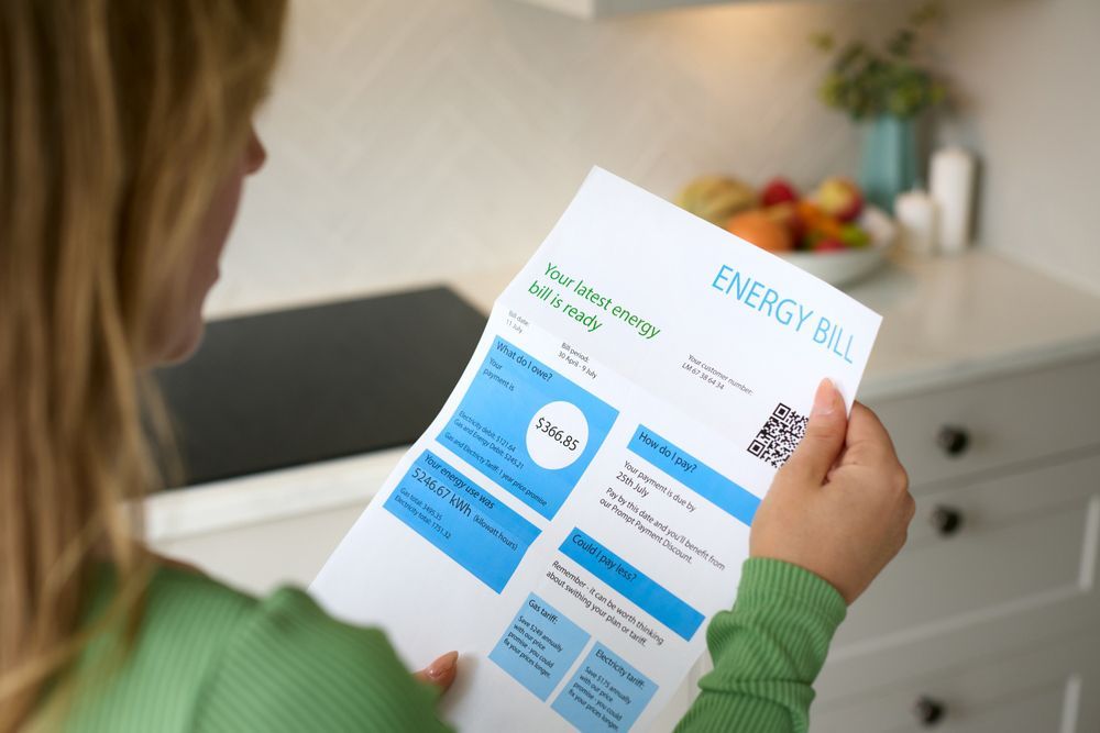 A woman is reading an energy bill in a kitchen.