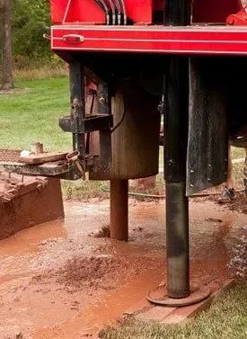 A red and black machine is digging a hole in the ground.