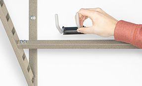 a person is holding a hook on a shelf .