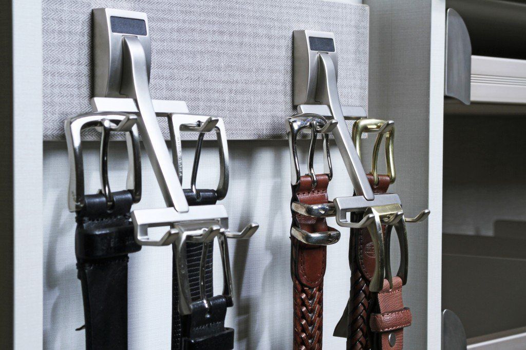 a bunch of belts are hanging hooks in a closet