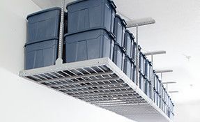 a ceiling rack filled with lots of storage bins in a garage .
