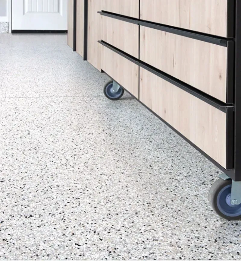 a close up of a cabinet with wheels on a coated garage floor .