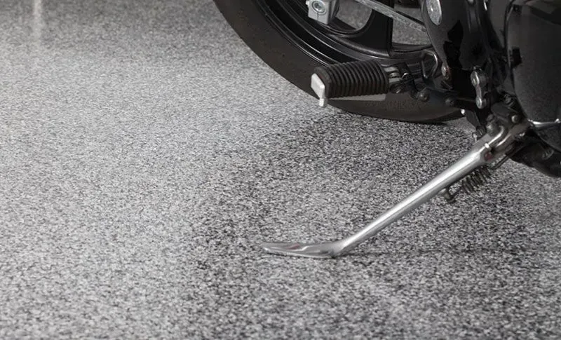 a motorcycle is parked on an epoxy floor coating in a garage .