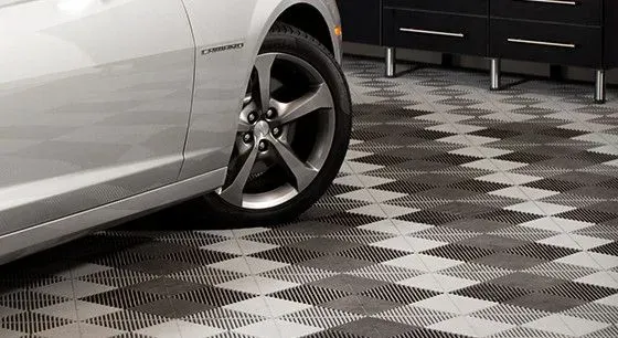 a silver car is parked in a garage with a tile floor .