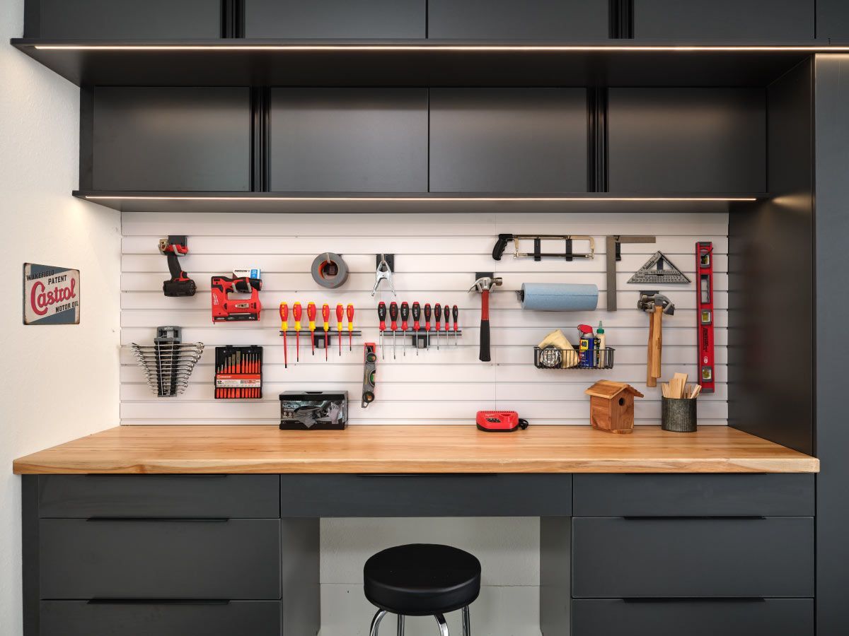 a garage with a wooden workbench, cabinets, and a stool .