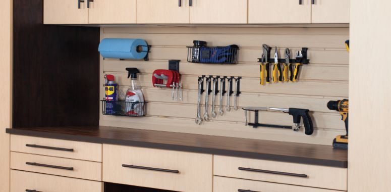 a garage workbench with lots of cabinets and drawers and a drill on the counter .