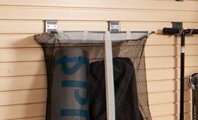 A mesh back storing yoga equipment hanging from a slatwall system