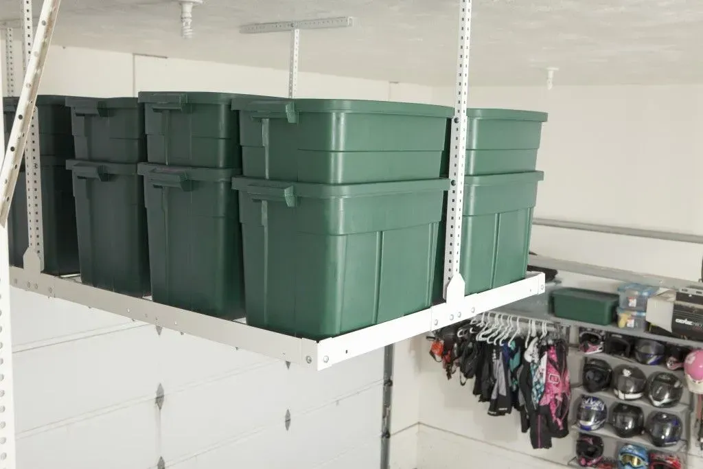 a bunch of green bins are stacked on top of each other on a shelf in a garage .