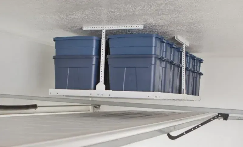 a bunch of blue bins are hanging from the ceiling of a garage .