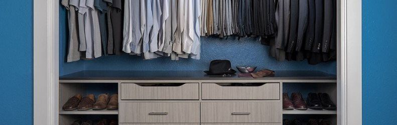 A walk in closet with blue walls and a dresser filled with clothes.