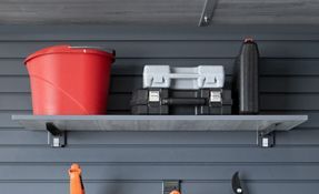 a shelf with a bucket and a toolbox on it in a garage .