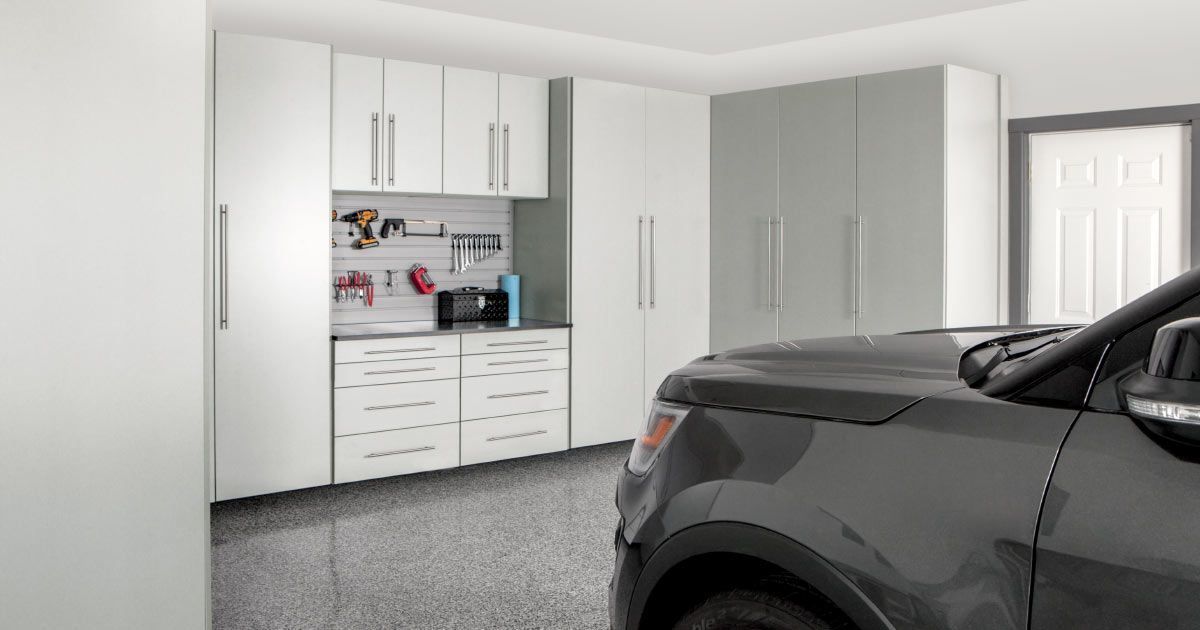 a black truck is parked in a garage with white cabinets .