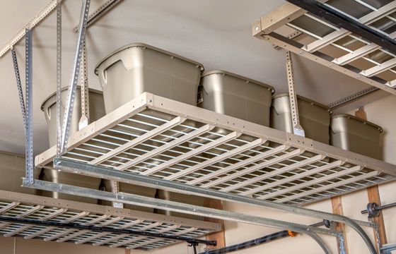 a garage with lots of overhead racks and bins hanging from the ceiling .