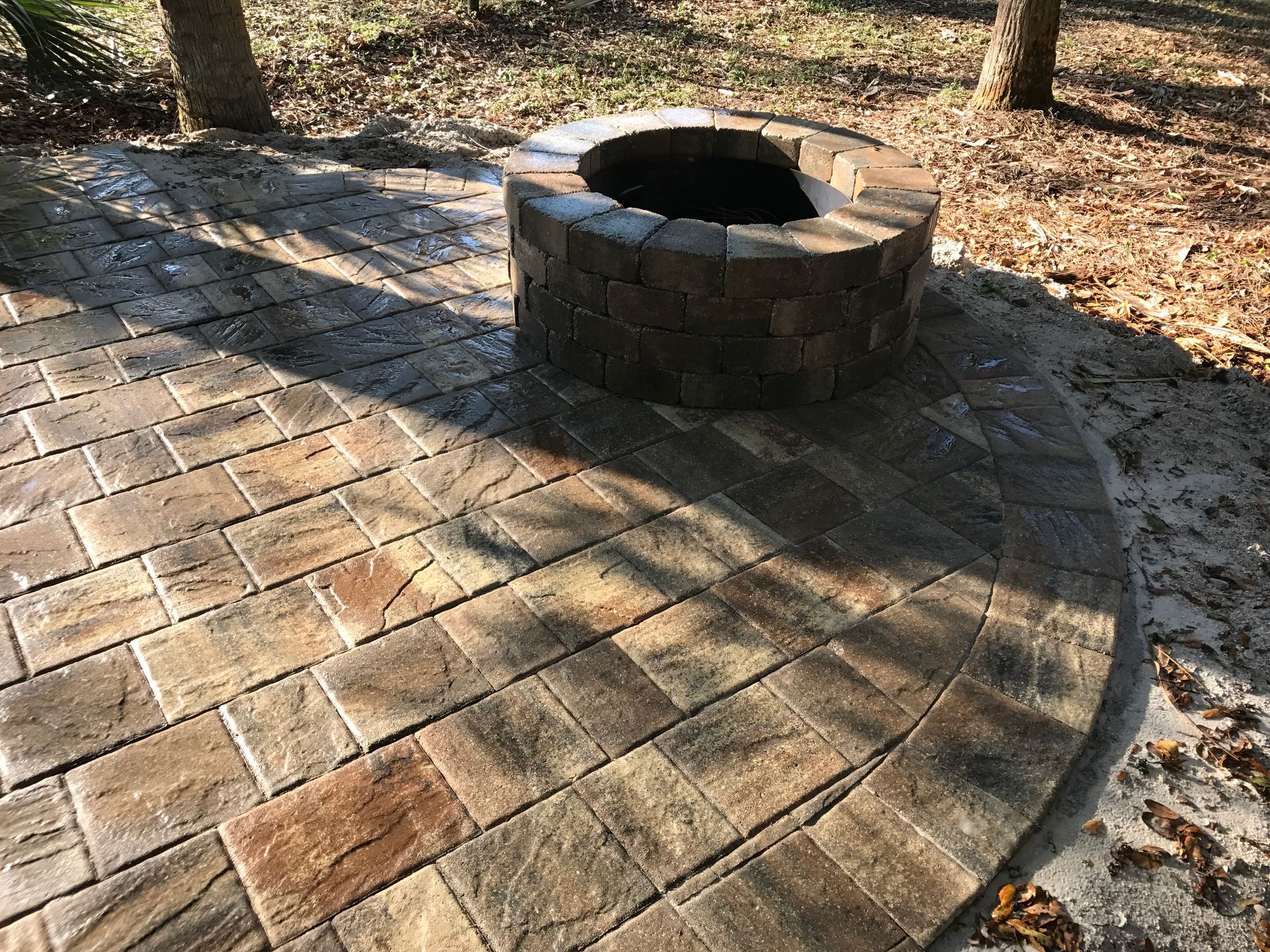 A fire pit is sitting on top of a brick patio.