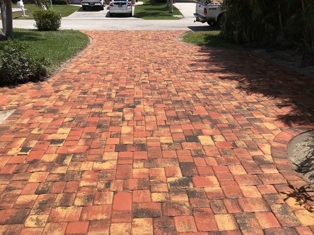 A brick driveway with cars parked on the side of it.
