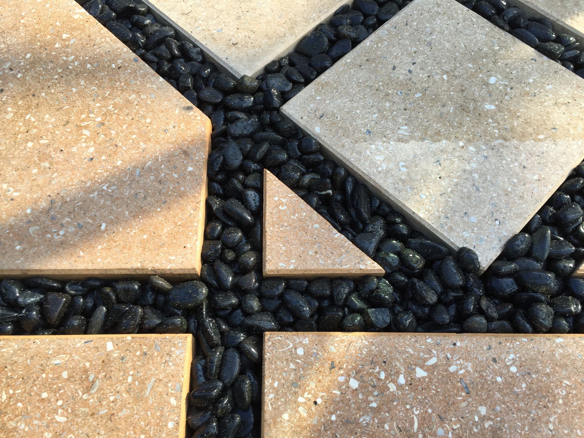A close up of a brick walkway with black rocks.