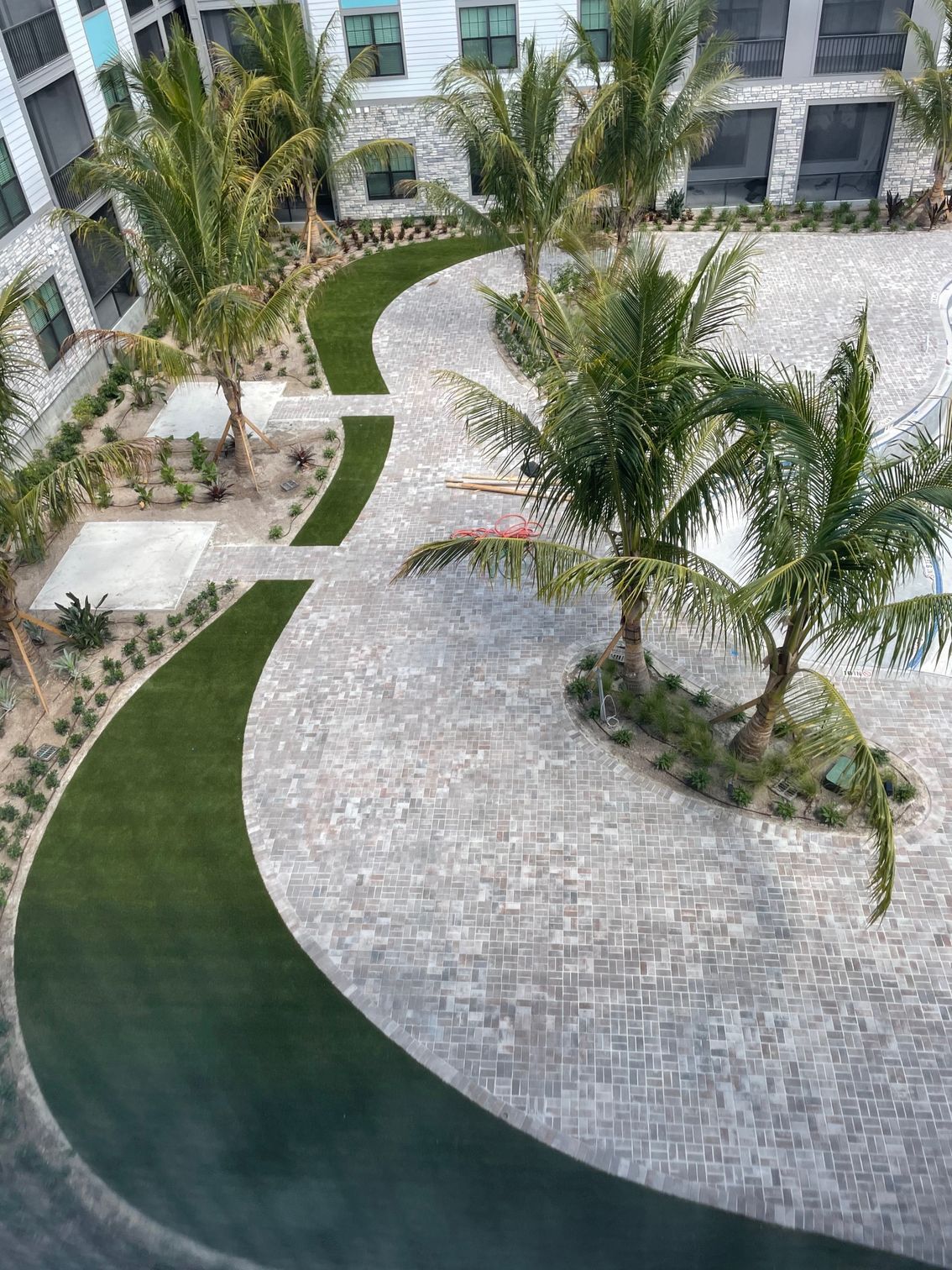An aerial view of a courtyard with palm trees and synthetic grass.